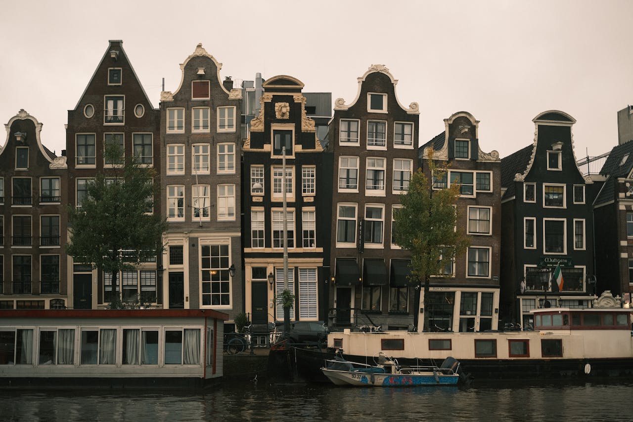 Charming view of iconic gabled canal houses and houseboats in Amsterdam.