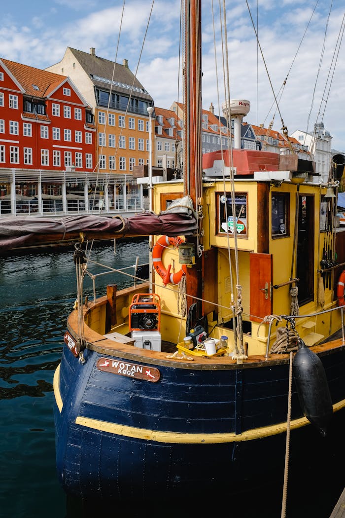 gallery-2 A vibrant boat docked at Nyhavn harbor in Copenhagen, Denmark, under a sunny sky.