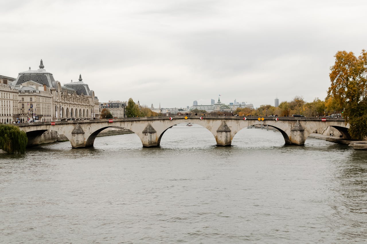 our-services-2 Historic Pont Neuf bridge in Paris spans the Seine River on a cloudy autumn day.