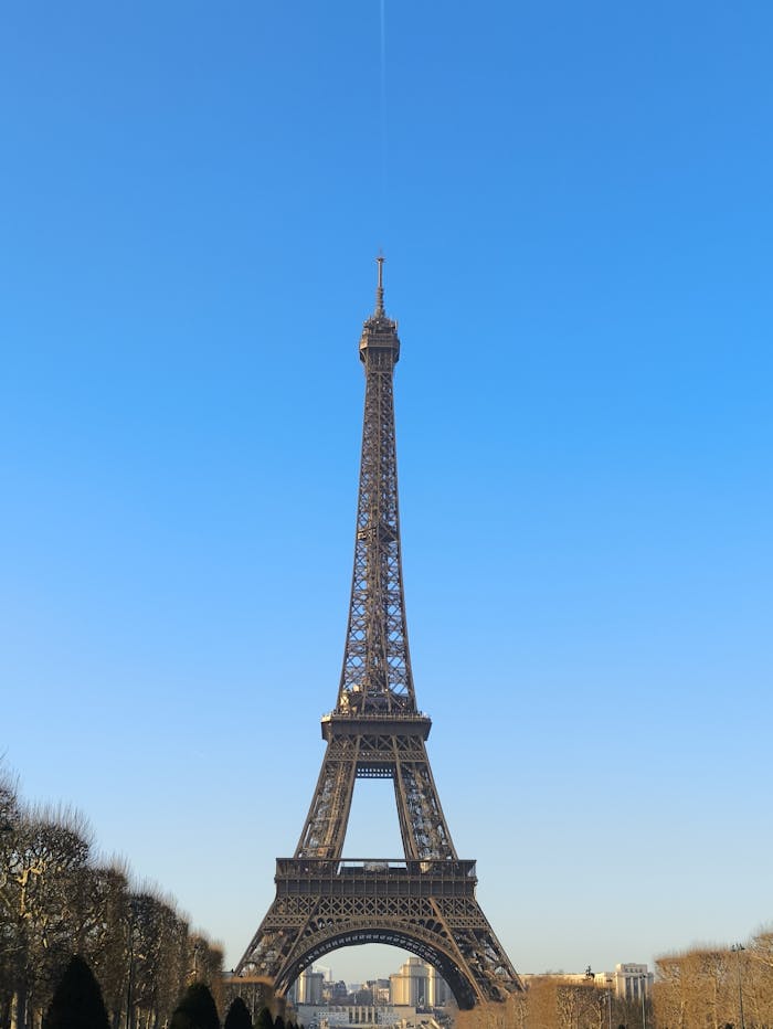 hero-img-01 Iconic Eiffel Tower in Paris under a clear blue sky, showcasing its architectural elegance.